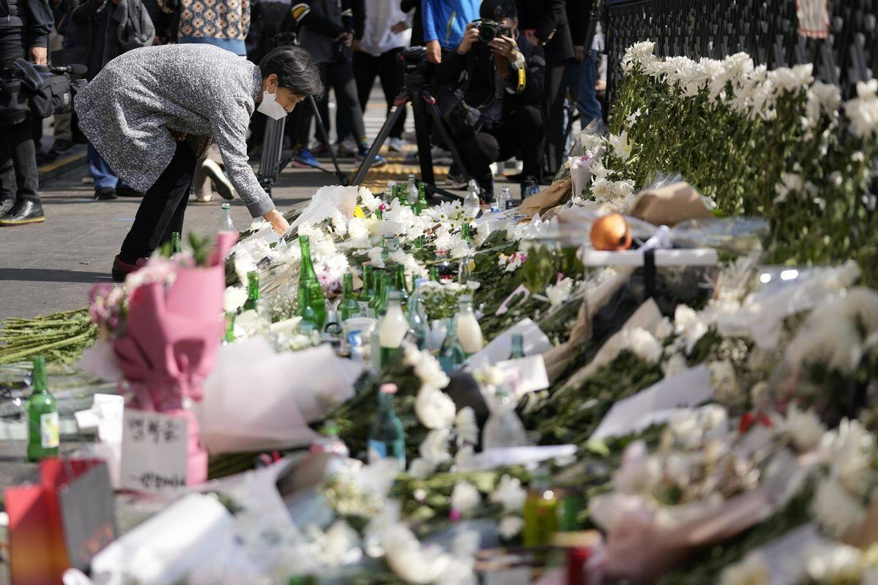 A mourner places flower to pay tribute to victims of a deadly accident following Saturday night’s Halloween festivities on the street near the scene in Seoul, South Korea, Monday, Oct. 31, 2022. Police are investigating what caused a crowd surge that killed more than 150 people during Halloween festivities in Seoul over the weekend in the country’s worst disasters in years. (AP Photo/Lee Jin-man)