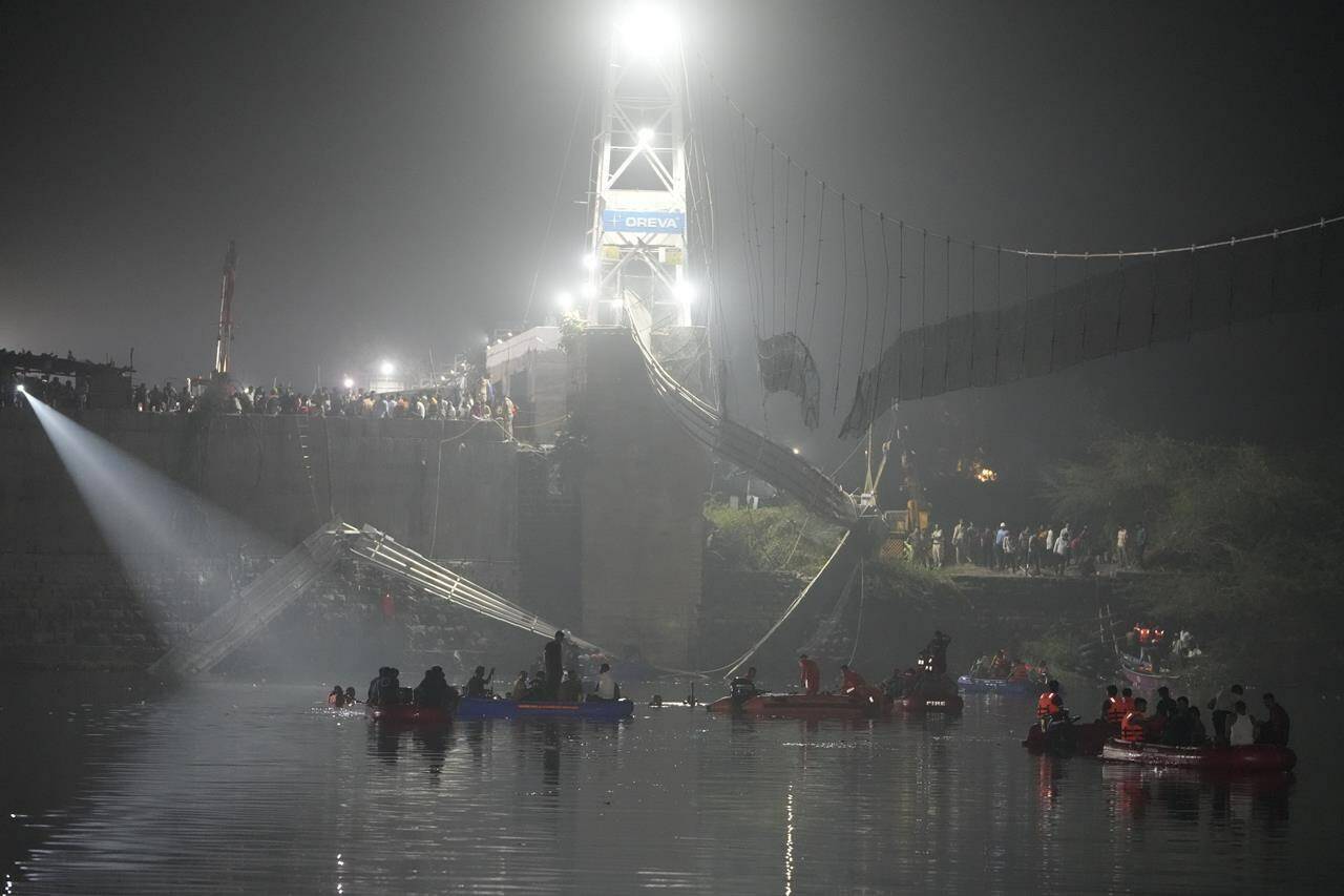 Rescuers on boats search in the Machchu river next to a cable suspension bridge that collapsed in Morbi town of western state Gujarat, India, Monday, Oct. 31, 2022. The century-old cable suspension bridge collapsed into the river Sunday evening, sending hundreds plunging in the water, officials said. (AP Photo/Ajit Solanki)