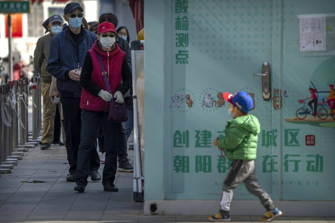 People wearing face masks stand in line for COVID-19 tests at a coronavirus testing site in Beijing, Tuesday, Nov. 1, 2022. Shanghai Disneyland was closed and visitors temporarily kept in the park for virus testing, the city government announced, while social media posts said some amusements kept operating for guests who were blocked from leaving. (AP Photo/Mark Schiefelbein)