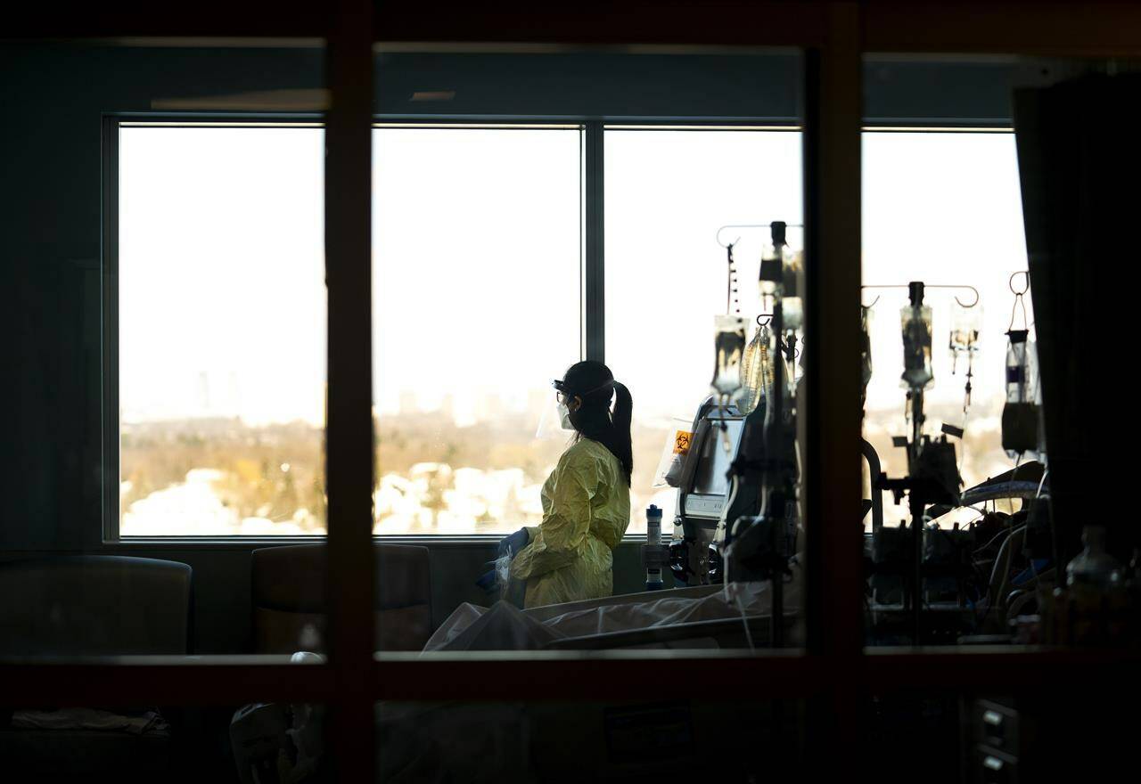 A registered nurse takes a moment to look outside while attending to a ventilated COVID-19 patient in the intensive care unit at the Humber River Hospital, in Toronto, Jan. 25, 2022. Canada’s health ministers are set to meet in British Columbia this week, four months after premiers from across the country converged on Victoria to show a united front of frustration over what they called a “crumbling” health-care system. THE CANADIAN PRESS/Nathan Denette