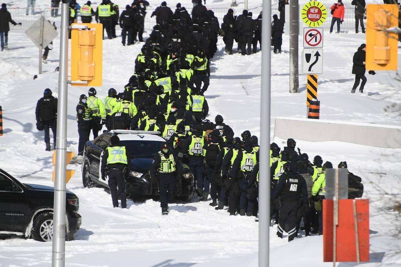A lineup of police officers assemble on Colonel By Drive near the truck blockade in Ottawa, on Friday, Feb. 18, 2022. Senior federal civil servants are testifying or the first time at the commission investigating the federal government’s invocation of the Emergencies Act last winter. THE CANADIAN PRESS/Justin Tang