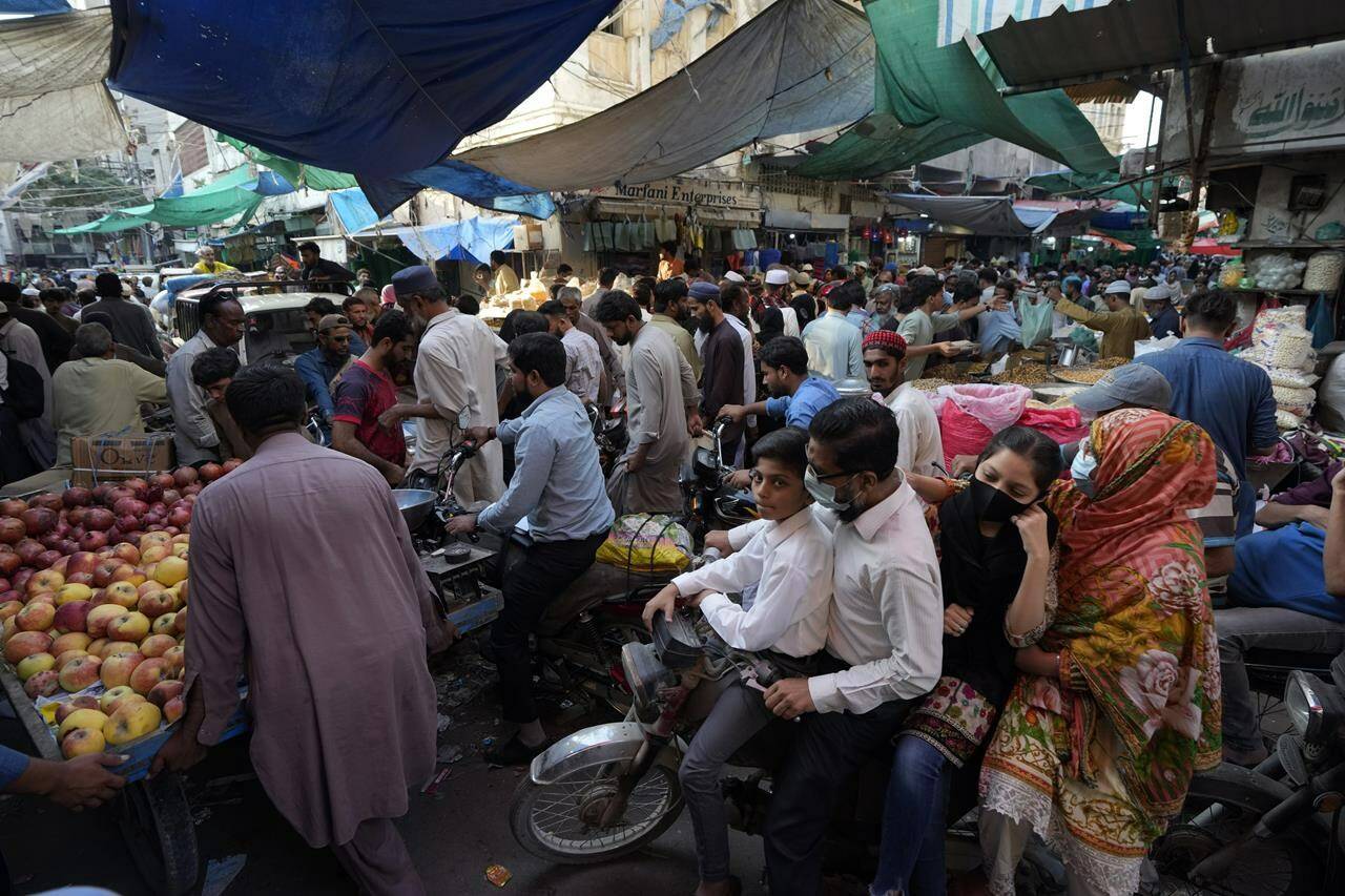 Pakistani people shops in the city of Karachi, Pakistan, Saturday, Nov. 12, 2022. The 8 billionth baby on Earth is about to be born on a planet that is getting hotter. But experts in climate science and population both say the two issues aren’t quite as connected as they seem. (AP Photo/Fareed Khan)