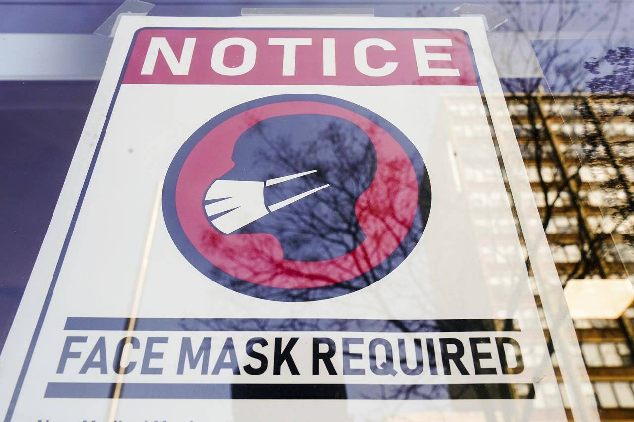 FILE - A sign requiring masks seen on a storefront in February 2022. Four groups in B.C. are calling on the province to re-introduce a mask mandate, in an open letter published Nov. 15, 2022. (AP Photo/Matt Rourke, File)