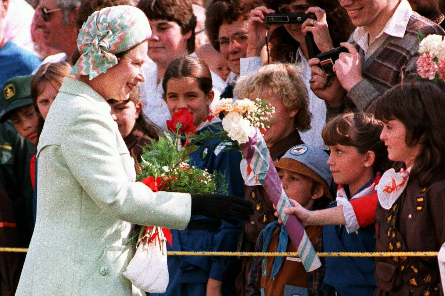 Queen Elizabeth II receives flowers from brownies and girl guides as she visits Brandon University in Brandon, MB, Oct. 5, 1984, for the dedication of the Queen Elizabeth II School of Music building. (CP PHOTO/Nick Didlick)