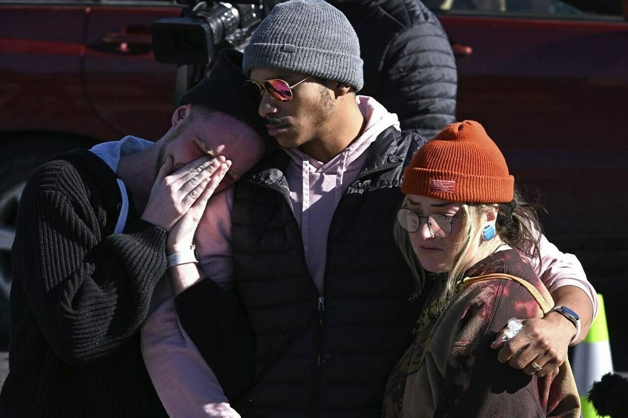 Tyler Johnston, left, his fiance Keenan Mestas-Holmes, center, and their friend Atlas Pretzeus hug one another while paying their respects at a makeshift memorial near Club Q on Sunday, Nov. 20, 2022 in Colorado Springs, Colo. The trio have close friends that were involved in the shooting. An attacker opened fire in a gay nightclub late Saturday night. (Helen H. Richardson/The Denver Post via AP)