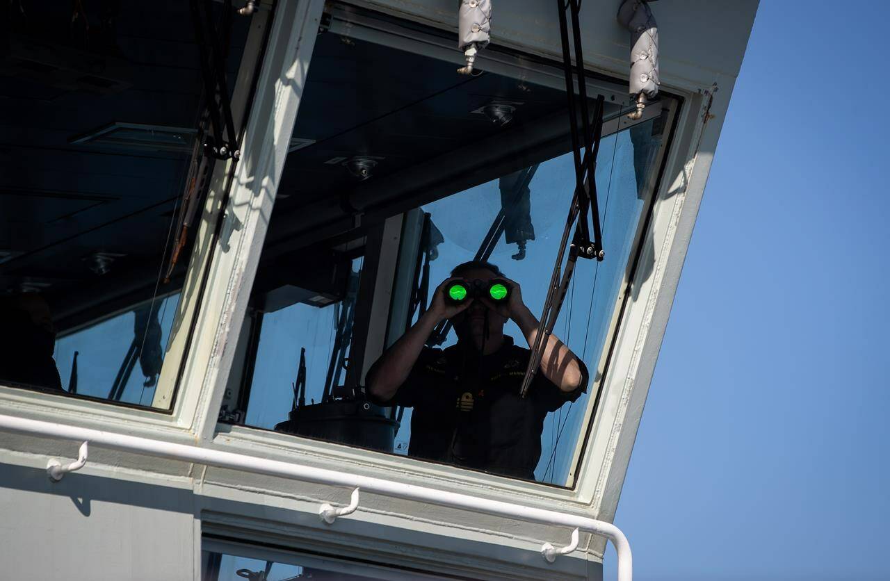 Cmdr. Corey Gleason, Commanding Officer of the Royal Canadian Navy’s newest Arctic and Offshore Patrol Ship, HMCS Harry DeWolf, uses binoculars as he looks out from the bridge while travelling on the Salish Sea from Vancouver to Victoria, B.C., Sunday, Oct. 3, 2021. A senior Canadian military official says Russia has started sending long-range bombers back across the Arctic toward North America following a pause during the early months of its war in Ukraine. THE CANADIAN PRESS/Darryl Dyck