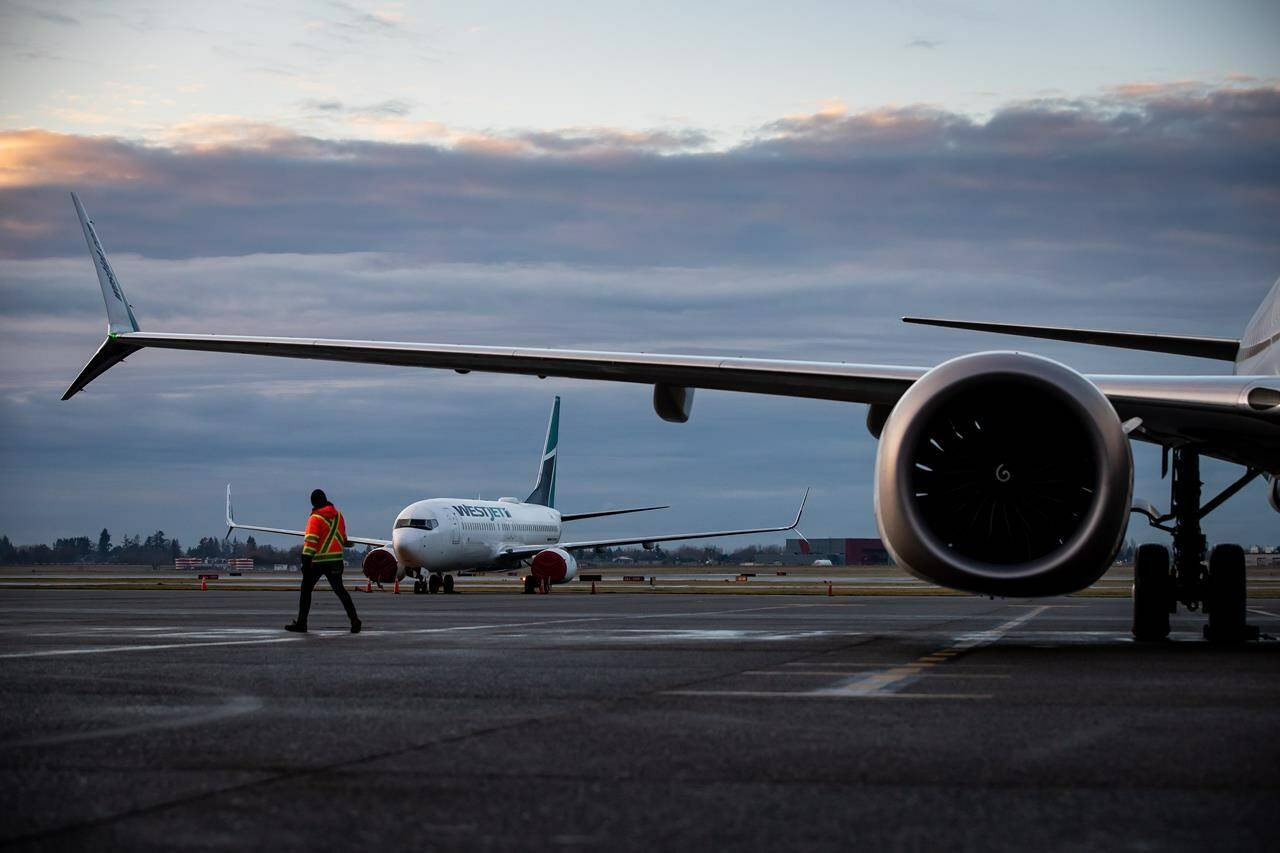 A ground worker walks under one of the wings of a WestJet Airlines Boeing 737 Max aircraft after it arrived at Vancouver International Airport, in Richmond, B.C., Thursday, Jan. 21, 2021. Canada’s Transport Minister met with airlines and airports to ensure reliable service for travellers ahead of what is expected to be a busy travel season. THE CANADIAN PRESS/Darryl Dyck