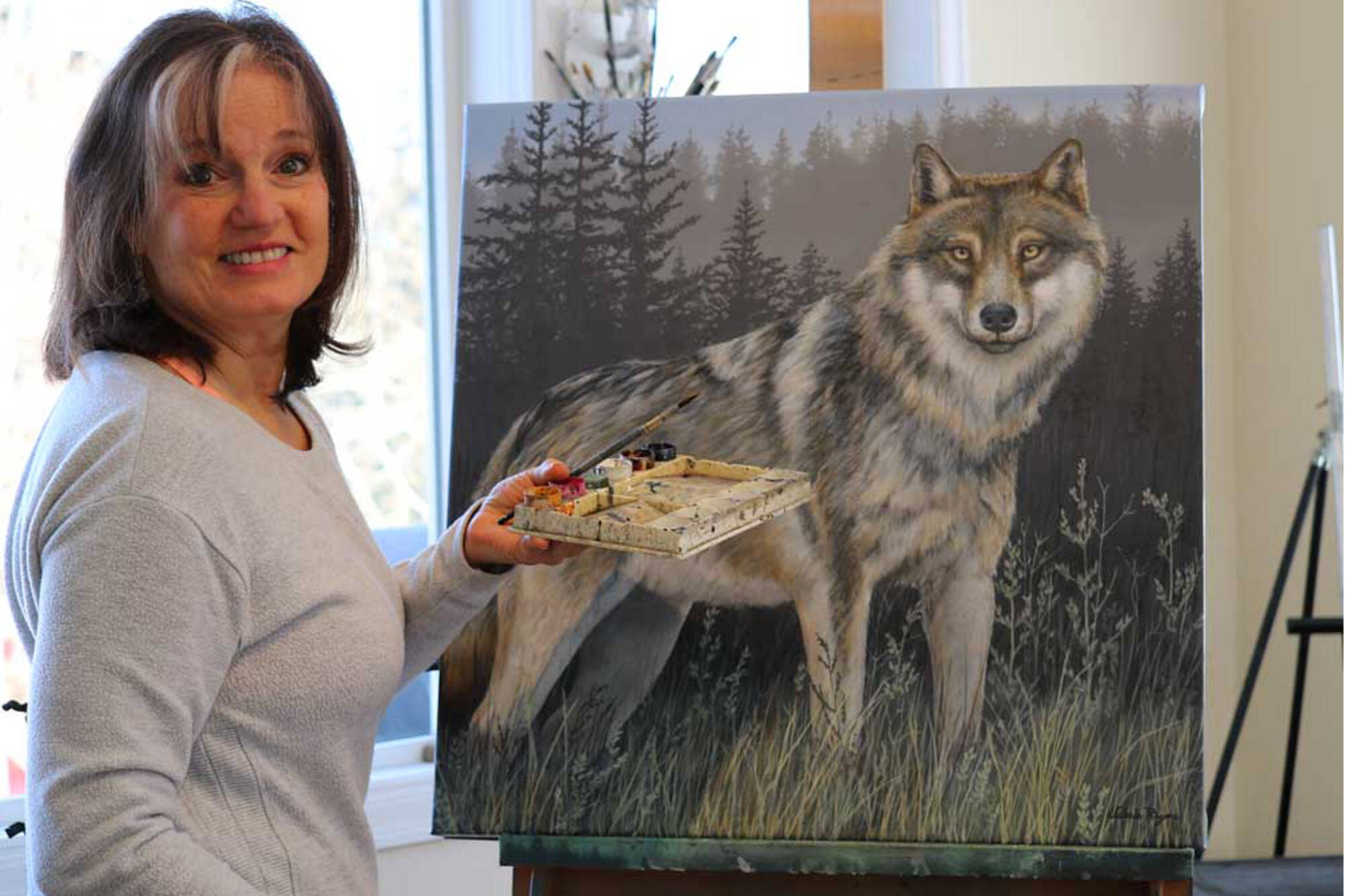 Renowned nature and wildlife artist Valerie Rogers works on a painting of a wolf in her Salmon Arm studio. (Photo contributed)
