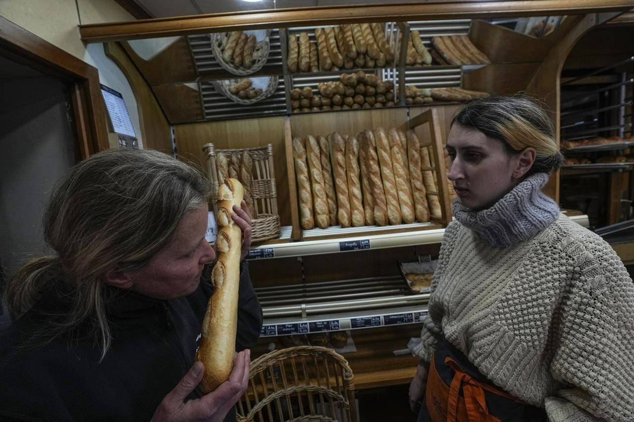 Bakery owner Florence Poirier, LEFT, smells the fresh baguette who comes out of the oven as Mylene Poirier stands next to her at a bakery, in Versailles, west of Paris, Tuesday, Nov. 29, 2022. The humble baguette — the crunchy ambassador for French baking around the world — is being added to the U.N.’s list of intangible cultural heritage as a cherished tradition to be preserved by humanity. UNESCO experts gathering Wednesday Nov. 30, 2022 in Morocco decided that the simple French flute deserved U.N. recognition. (AP Photo/Michel Euler)
