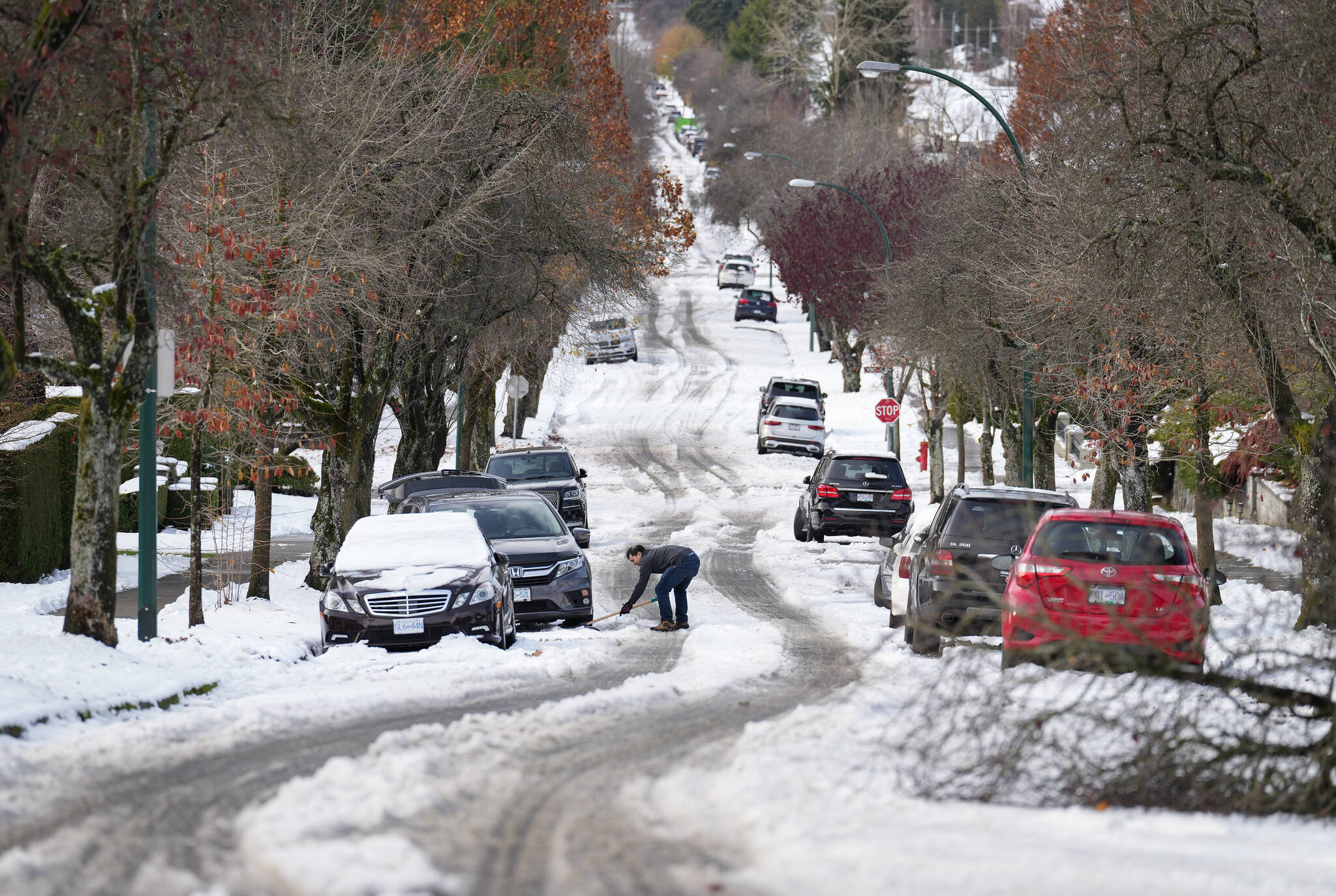 A man digs out snow from under a car stuck on a street in the aftermath of a snowstorm, in Vancouver, B.C., Wednesday, Nov. 30, 2022. THE CANADIAN PRESS/Darryl Dyck