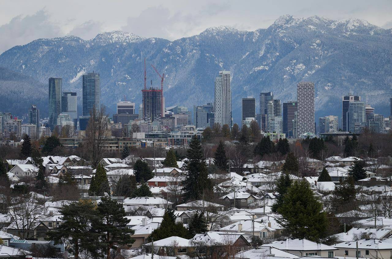 Snow-covered houses and the downtown skyline are seen after a snowstorm, in Vancouver on November 30, 2022. British Columbia’s property assessment agency is warning homeowners that figures released next month will likely be higher than the current market value.THE CANADIAN PRESS/Darryl Dyck