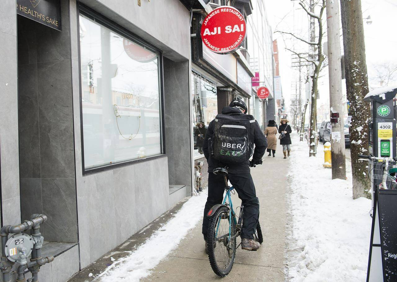 An Uber Eats courier is pictured as they pick up an order for delivery. (THE CANADIAN PRESS/Nathan Denette)