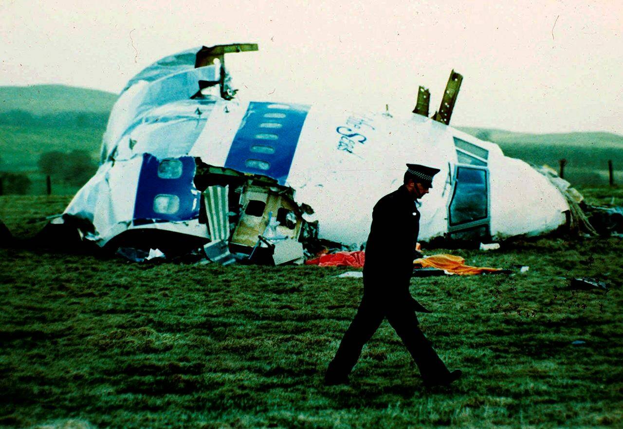 FILE - A police officer walks by the nose of Pan Am flight 103 in a field near the town of Lockerbie, Scotland where it lay after a bomb aboard exploded, killing a total of 270 people, Wednesday, Dec. 21, 1988. Authorities in Scotland on Sunday, Dec. 11, 2022 say the Libyan man suspected of making the bomb that destroyed a passenger plane over Lockerbie, Scotland, in 1988 is in U.S. custody. Scotland’s Crown Office and Procurator Fiscal Service said in a statement that the families of those who died had been told the news. (AP Photo/Martin Cleaver, File)