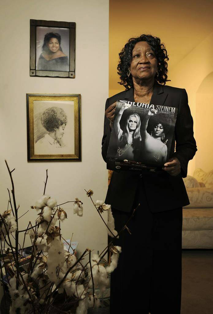 Dorothy Pitman Hughes is pictured in her St. Johns, Fla., home on Sept. 24, 2013, with a poster using a 1970s image of herself and Gloria Steinem. Hughes, a pioneering Black feminist, child welfare advocate and activist who co-founded Ms. Magazine with Steinem, formed a powerful speaking partnership with her and appeared with her in one of the most iconic photos of the feminist movement, has died. Hughes died Dec. 1, 2022, in Tampa, Fla. She was 84. (Bob Self/The Florida Times-Union via AP)