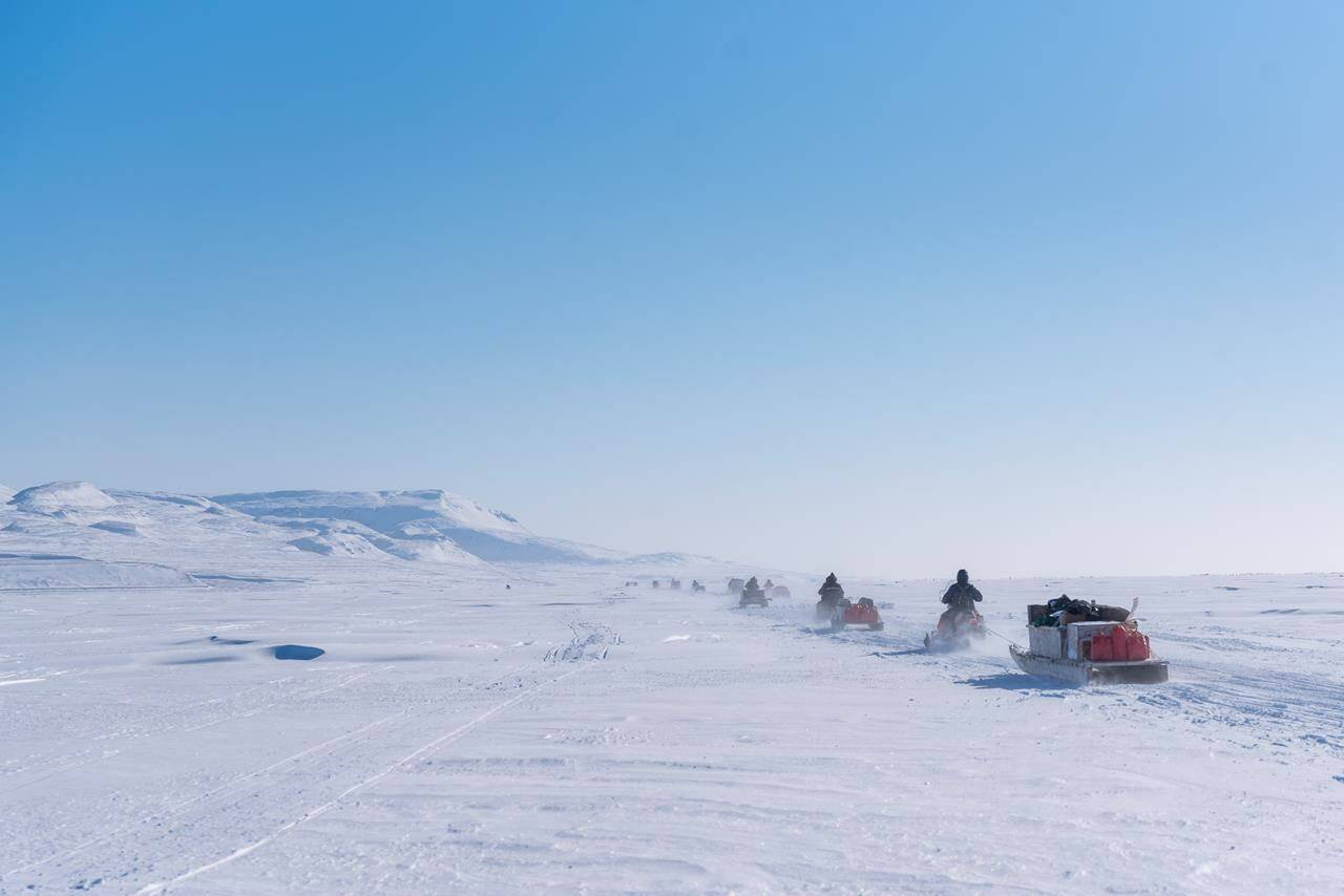 A convoy of support snowmobiles with qamutiks in tow, head toward the first Nunavut Quest camp, roughly 50km outside of Arctic Bay, Nunavut on Monday, April 18, 2022. A new report details how widespread changes in the Arctic, from warming air temperatures to sea-ice loss, have affected animals, plants and people living there. THE CANADIAN PRESS/Dustin Patar