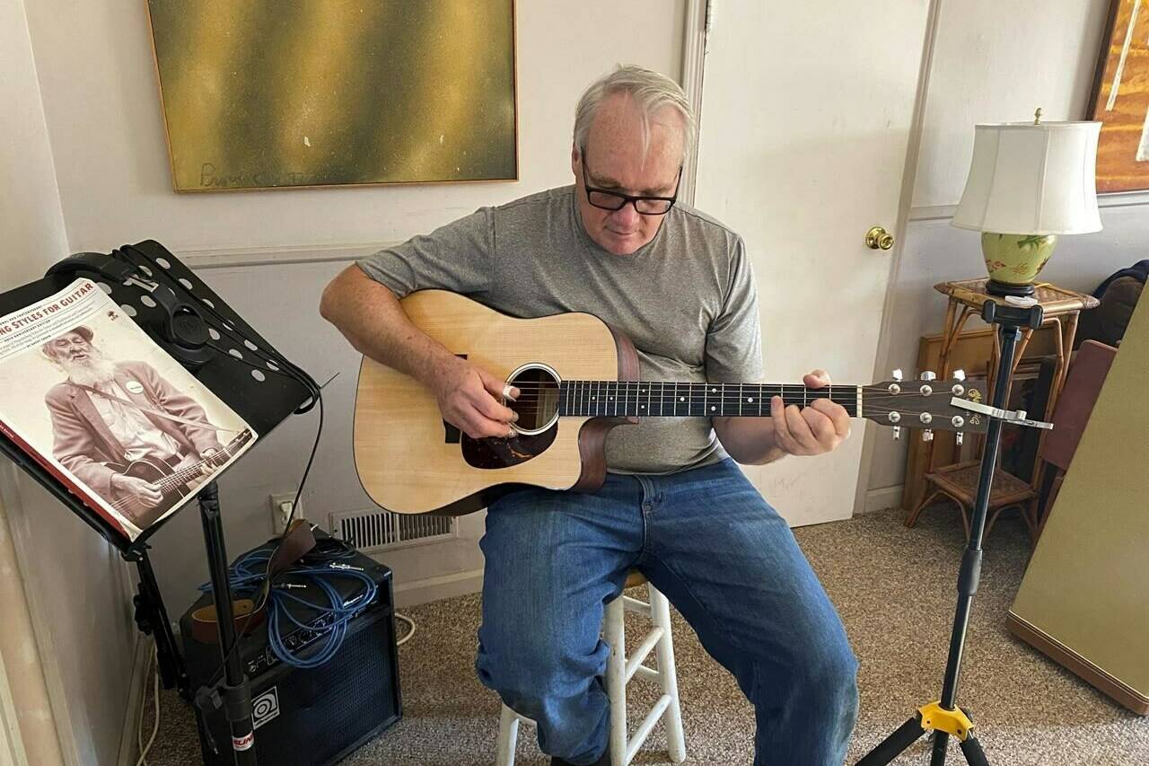 Bob Dorobis plays his guitar at home in Middletown, N.J., on Dec. 4, 2022. Dorobis redoubled his efforts to learn fingerpicking during the pandemic. (Jeanann Dorobis via AP)