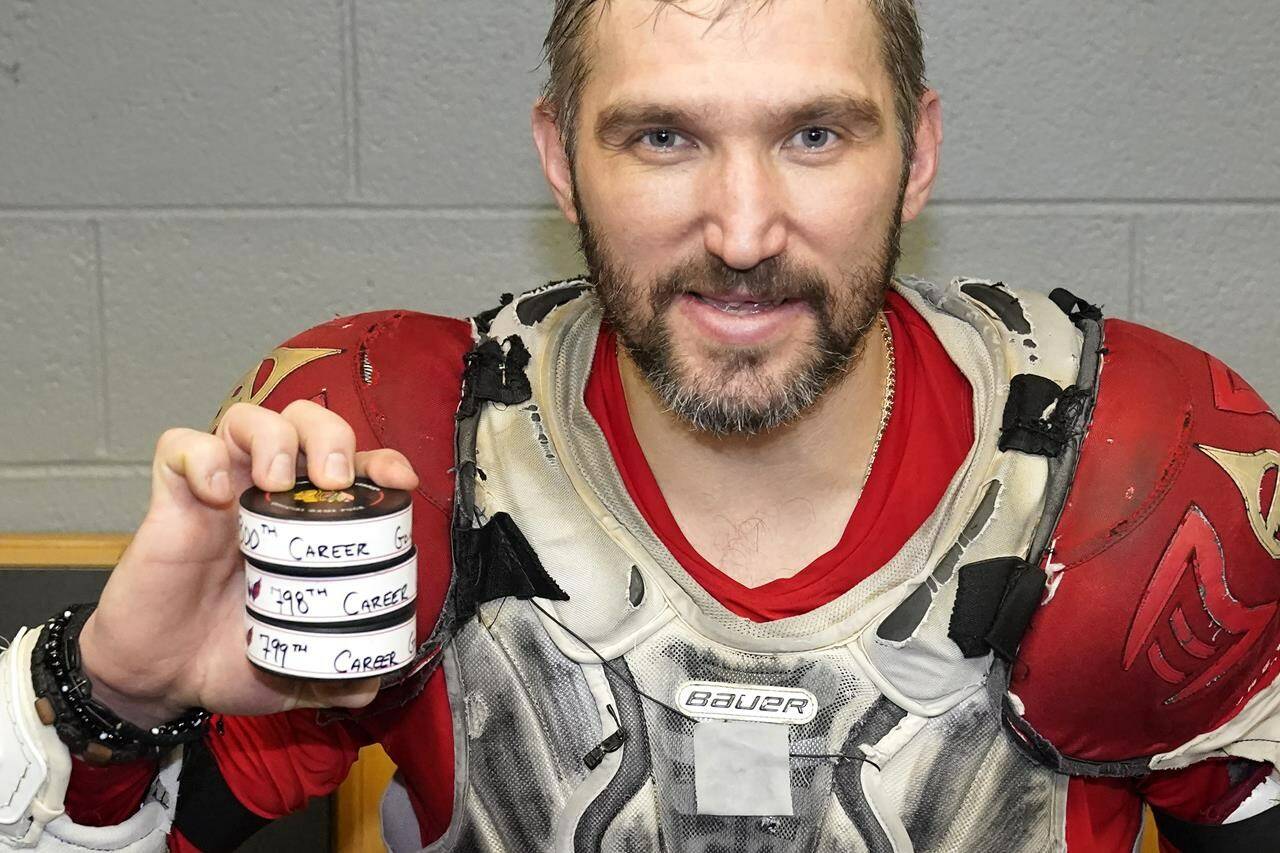 Washington Capitals’ Alex Ovechkin holds his 798, 799, and 800th career goal pucks in the locker room after an NHL hockey game against the Chicago Blackhawks Tuesday, Dec. 13, 2022, in Chicago. (AP Photo/Charles Rex Arbogast)