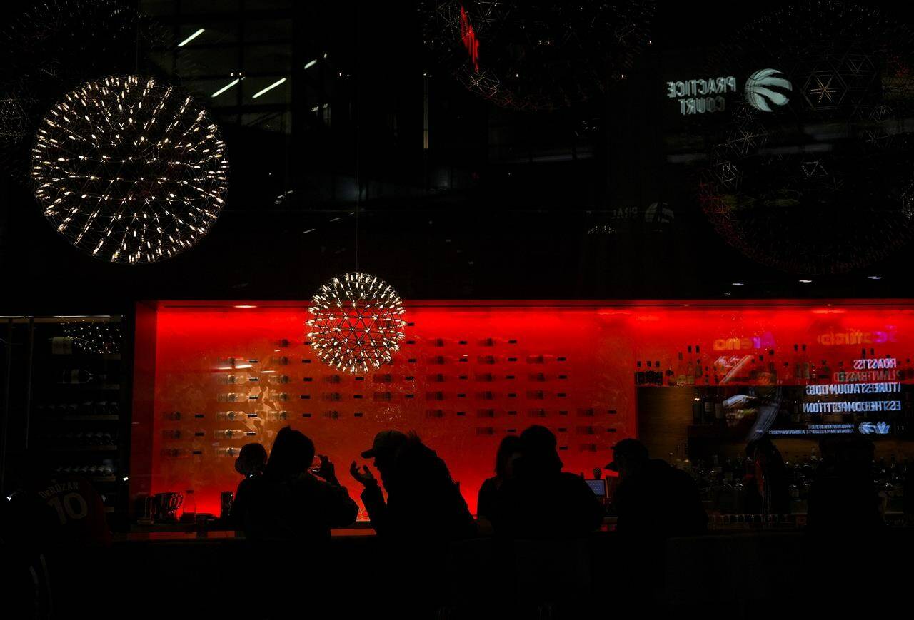 People are silhouetted as they sit in a bar having a drink in Toronto on Wednesday, March 30, 2022. THE CANADIAN PRESS/Nathan Denette
