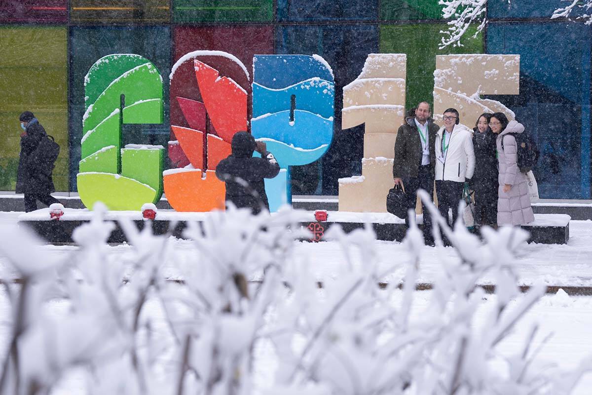Delegates take souvenir photos during a snowfall outside the convention centre at the COP15 UN conference on biodiversity in Montreal, Friday, Dec. 16, 2022. THE CANADIAN PRESS/Paul Chiasson