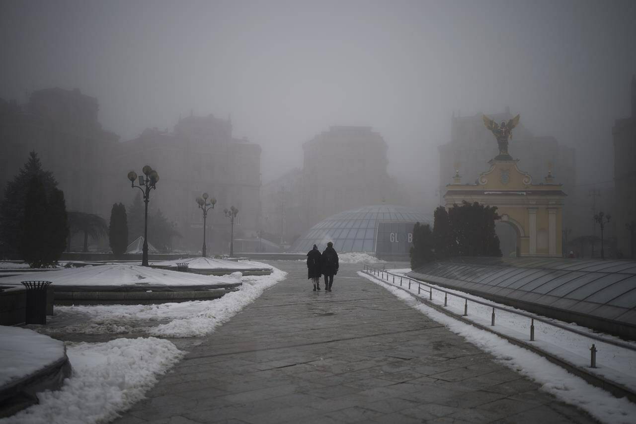 A couple walks through an empty Independence Square during an air raid alarm in Kyiv, Ukraine, Saturday, Dec. 17, 2022. (AP Photo/Felipe Dana)