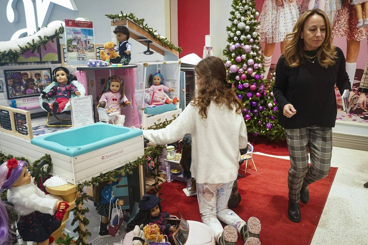 Jamie Cygielman, right, general manager and president at American Girl, leaves a youngster browsing the company’s latest holiday showcase doll set, Friday, Dec. 2, 2022, in New York. Cygielman said roughly half its sales went to adults after a relaunch of the first six American Girl dolls in May 2021 to celebrate its 35th anniversary. (AP Photo/Bebeto Matthews)