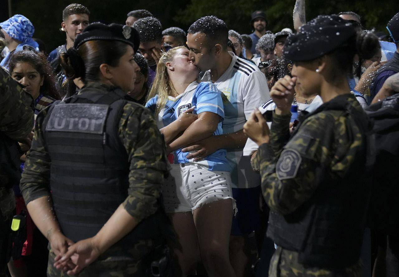 Fans kiss while waiting for the arrival of the Argentine soccer team that won the World Cup outside the AFA training grounds in Buenos Aires, Argentina, Tuesday, Dec. 20, 2022. (AP Photo/Matilde Campodonico)