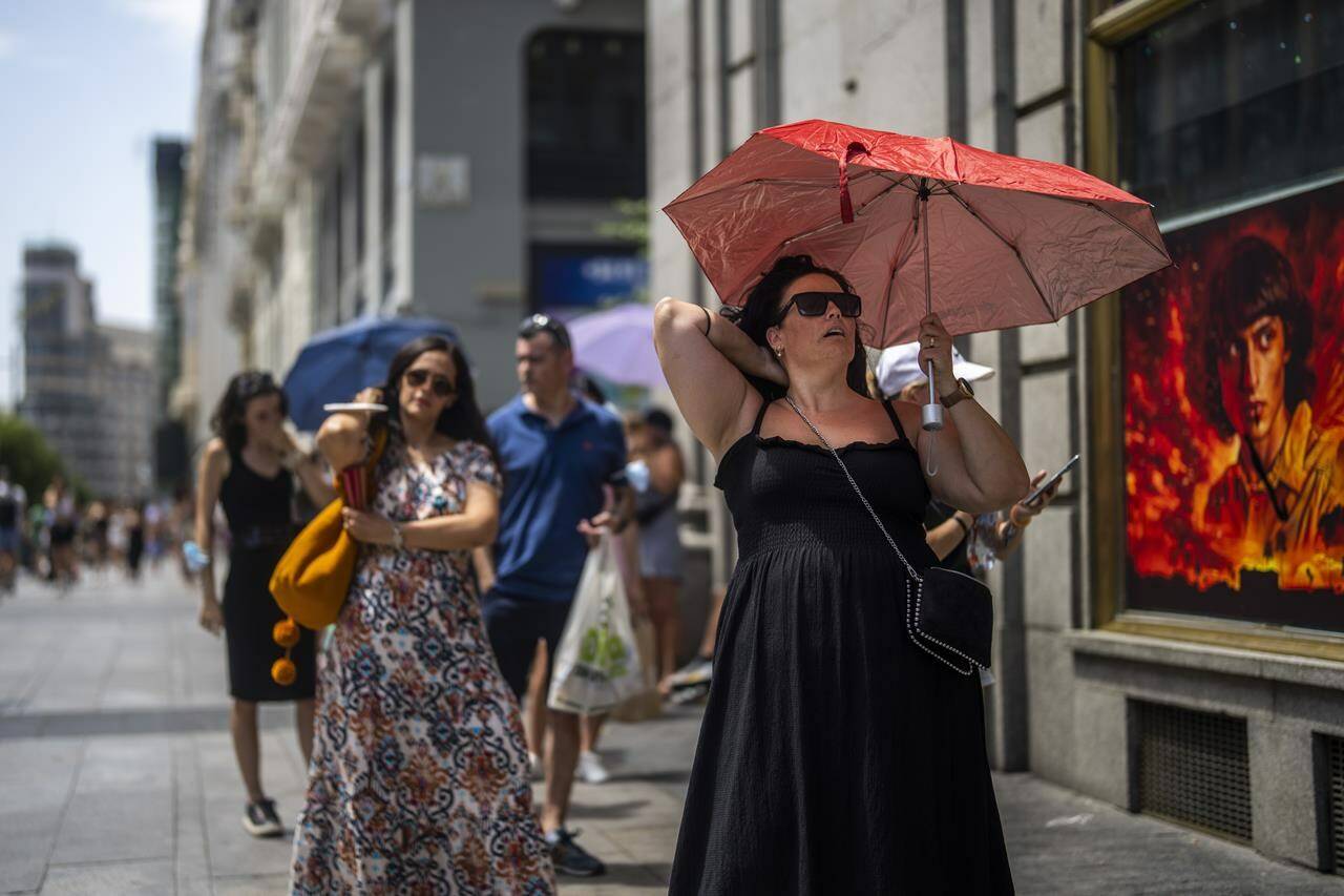 FILE - A woman holds an umbrella to shelter from the sun during a hot sunny day in Madrid, Spain, Monday, July 18, 2022. Spain’s national weather service said preliminary data indicates that 2022 will finish with average daily temperatures above 15 degrees Celsius (59 degrees Fahrenheit) for the first time since records started in 1961. It says that the four hottest years on record for the southern European country have all come since 2015. (AP Photo/Manu Fernandez, File)