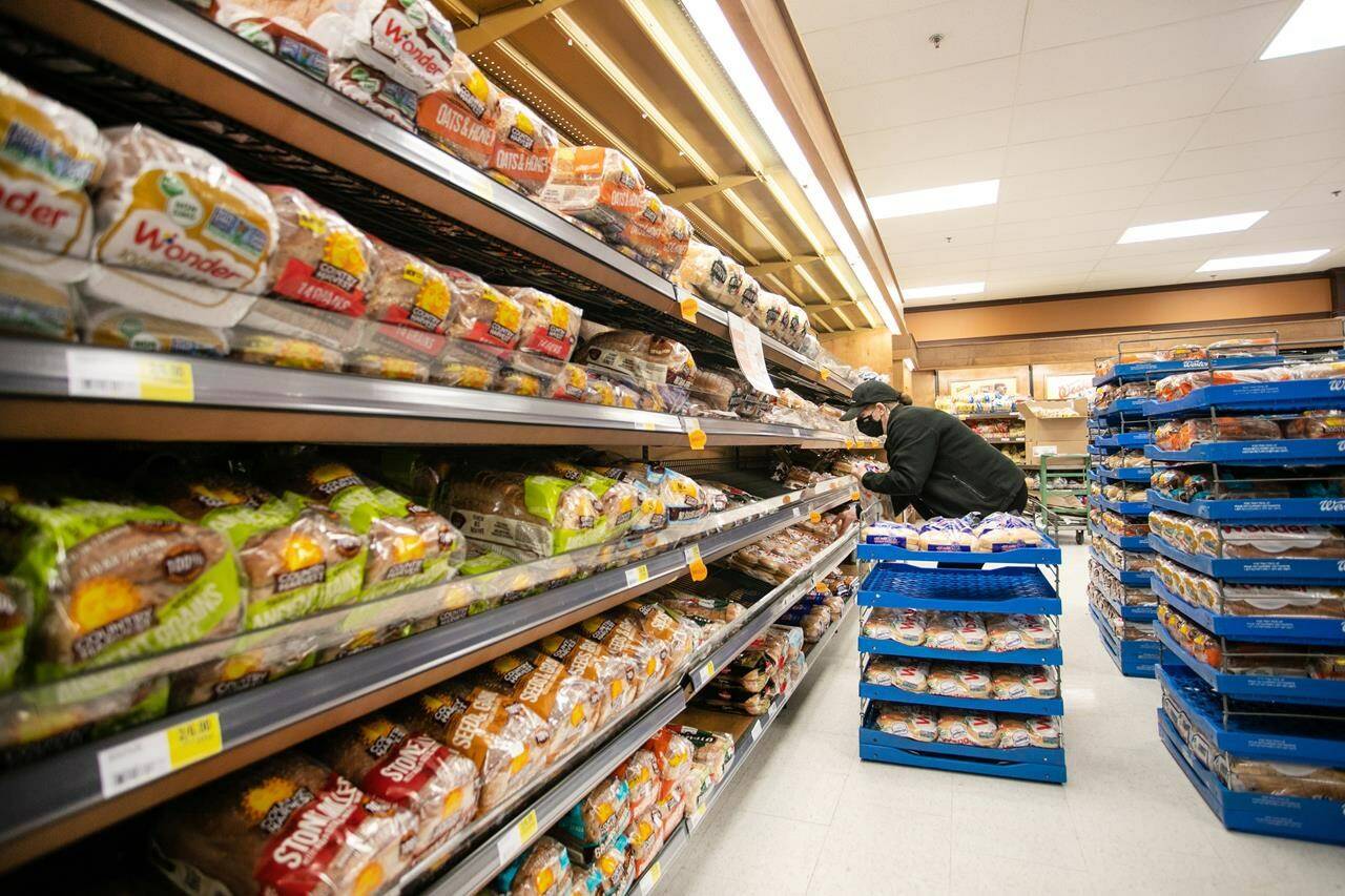 A worker re-stocks shelves in the bakery and bread aisle at an Atlantic Superstore in Halifax, N.S., on Friday, Jan. 28, 2022. How those wheat kernels end up in a loaf of bread — and why prices have risen this year — is an odyssey involving growers and grain handlers, rail cars and flour mills, and bakeries and supermarkets. THE CANADIAN PRESS/Kelly Clark