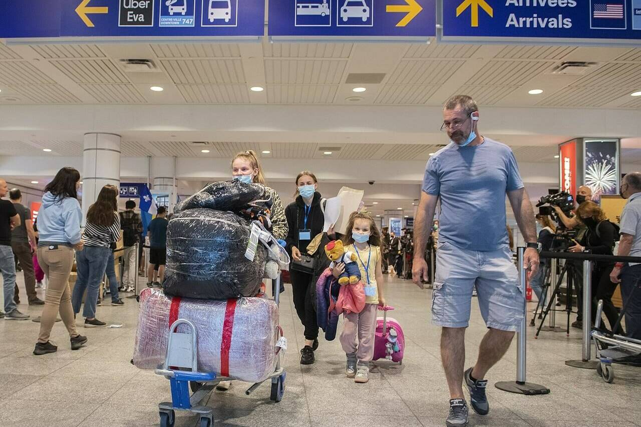 Ukrainian nationals fleeing the ongoing war in Ukraine, left, arrive in Montreal, Sunday, May 29, 2022. Canada’s population experienced a surprise boom in the third quarter, increasing at the fastest quarterly rate since 1957. The federal agency is attributing the boom to a rise in non-permanent residents, including work permit holders and refugees fleeing the Russian invasion of Ukraine. THE CANADIAN PRESS/Graham Hughes