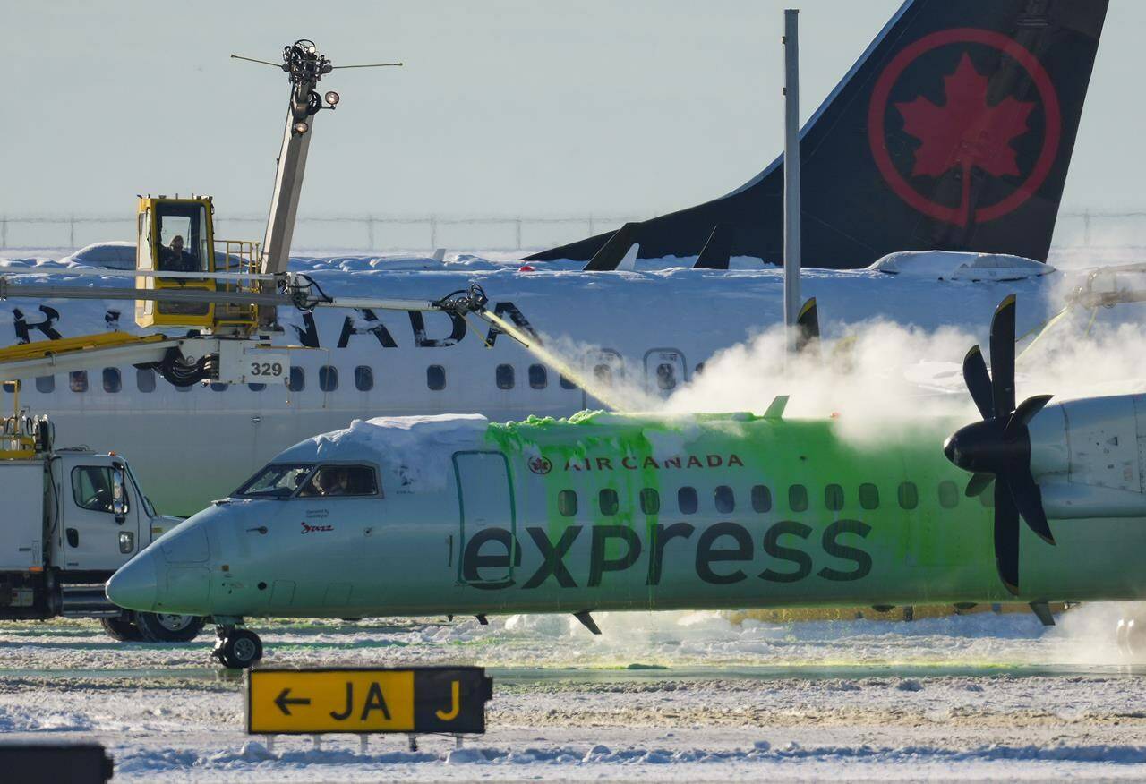 An Air Canada aircraft is de-iced at Vancouver International Airport in Richmond, B.C., Wednesday, Dec. 21, 2022. A major winter storm bearing down on Toronto is adding to the calamity in Canadian airports already plagued by flight cancellations and delays set off early this week by heavy snow in Vancouver.THE CANADIAN PRESS/Darryl Dyck