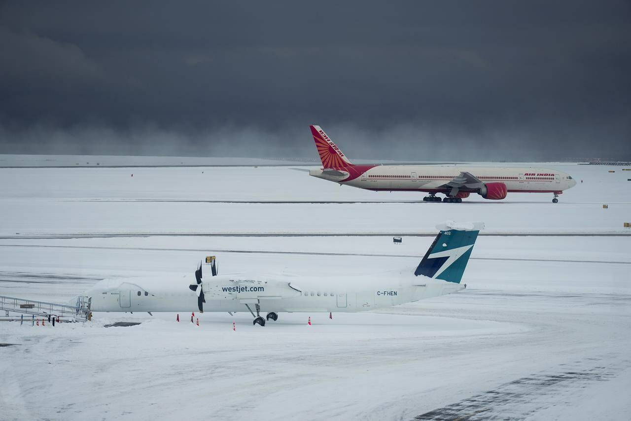Westjet and Air India aircraft sit idle at Vancouver International Airport after a snowstorm crippled operations leading to cancellations and major delays, in Richmond, B.C., Tuesday, Dec. 20, 2022. The holiday plans of thousands of people have been disrupted as bad weather forces the cancellation of large swathes of flights across the country. THE CANADIAN PRESS/Darryl Dyck