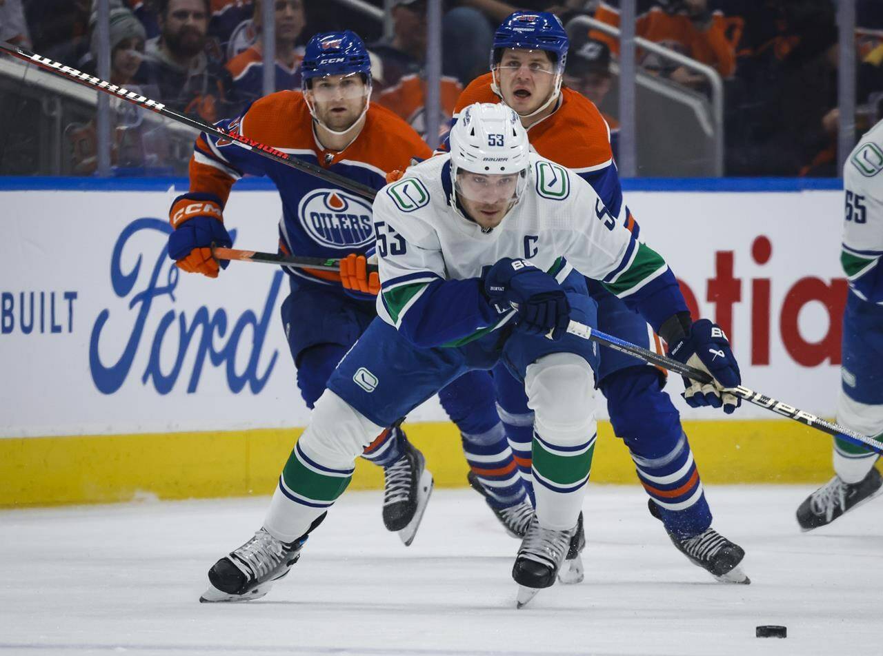 Vancouver Canucks forward Bo Horvat, centre, is chased by Edmonton Oilers defenceman Markus Niemelainen, left, and forward Mattias Janmark during first period NHL hockey action in Edmonton, Friday, Dec. 23, 2022. THE CANADIAN PRESS/Jeff McIntosh
