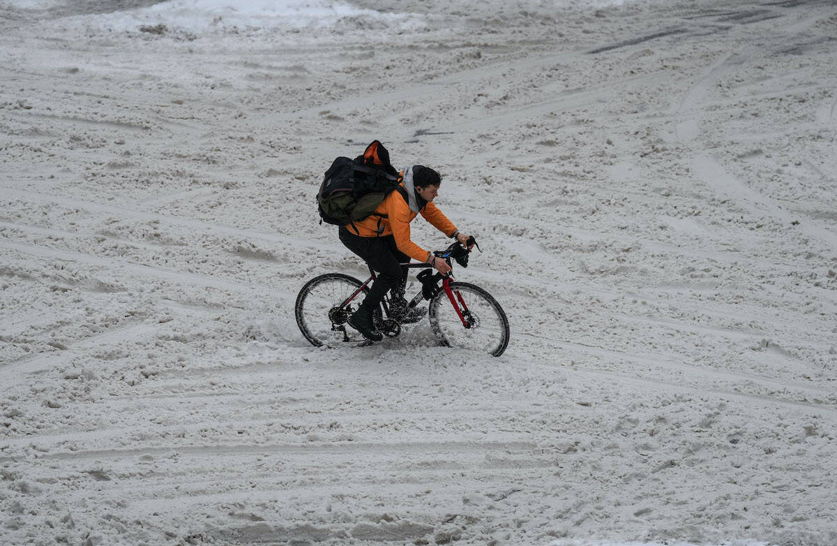 A cyclist navigates through the snow on an unplowed Robson Street as freezing rain falls in downtown Vancouver, on Friday, December 23, 2022. THE CANADIAN PRESS/Darryl Dyck