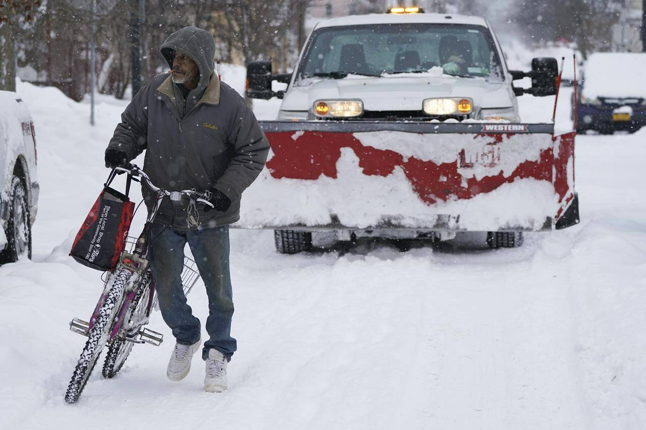 Carmelo Santiago pushes his bicycle down Rhode Island Street in Buffalo, N.Y., on his way back from a store where he ventured out to restock on supplies, Monday, Dec. 26, 2022. (Derek Gee/The Buffalo News via AP)