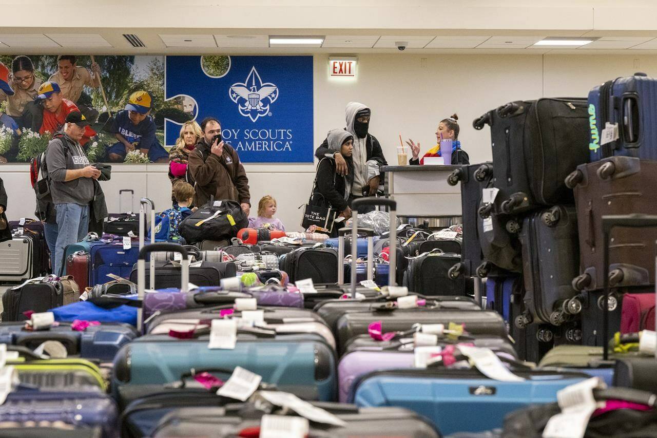 A Southwest Airlines employee tries to help travelers find their lost baggage at Midway International Airport, Monday, Dec. 26, 2022, in Chicago. (Tyler Pasciak LaRiviere/Chicago Sun-Times via AP)