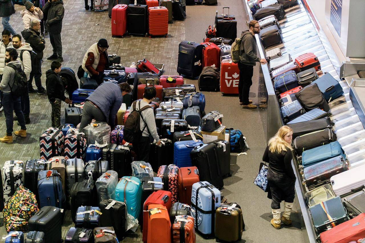 Luggage bags are amassed in the bag claim area at Toronto Pearson International Airport, as a major winter storm disrupts flights in and out of the airport, in Toronto, Saturday, Dec. 24, 2022. THE CANADIAN PRESS/Cole Burston