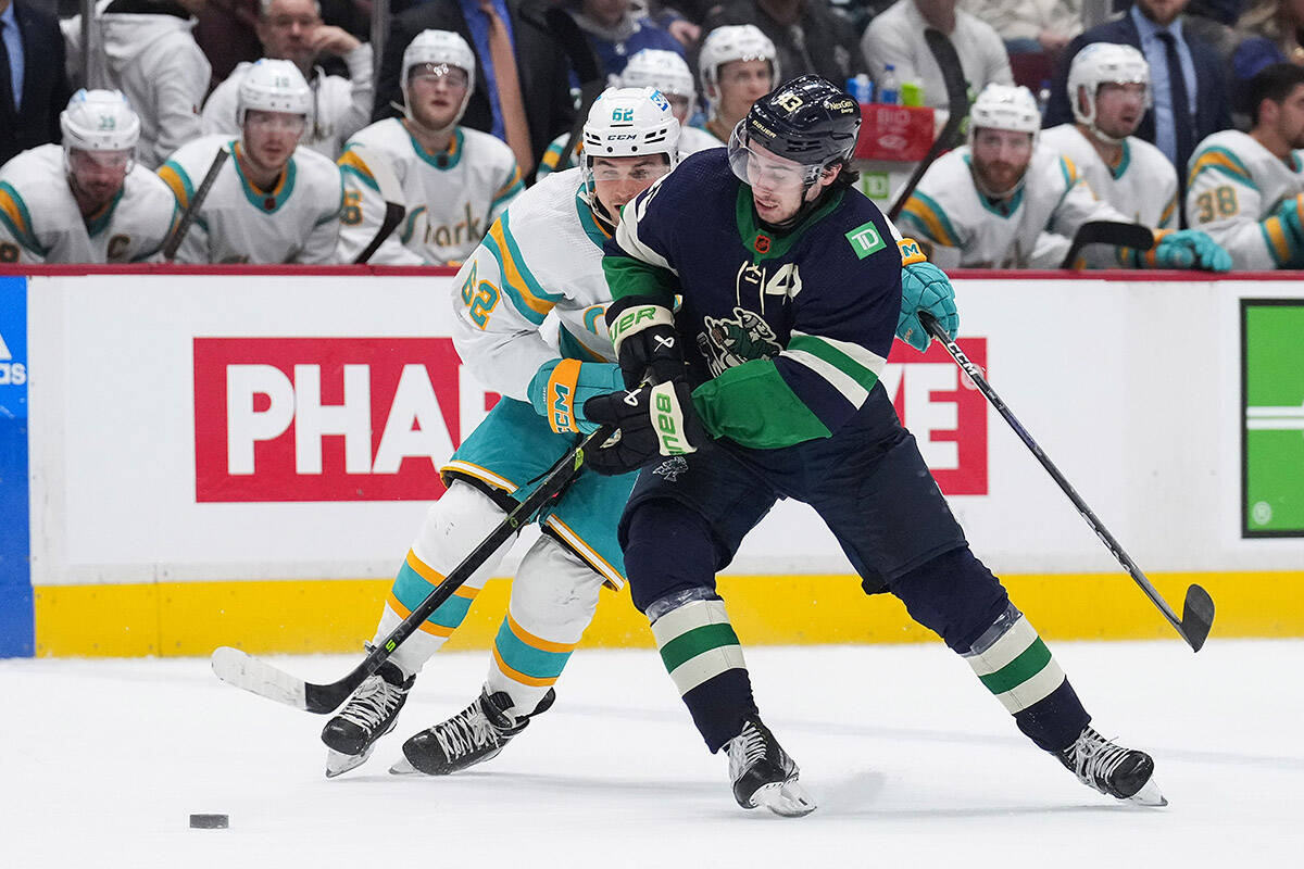Vancouver Canucks’ Quinn Hughes, front, and San Jose Sharks’ Kevin Labanc vie for the puck during the second period of an NHL hockey game in Vancouver, on Tuesday, December 27, 2022. THE CANADIAN PRESS/Darryl Dyck