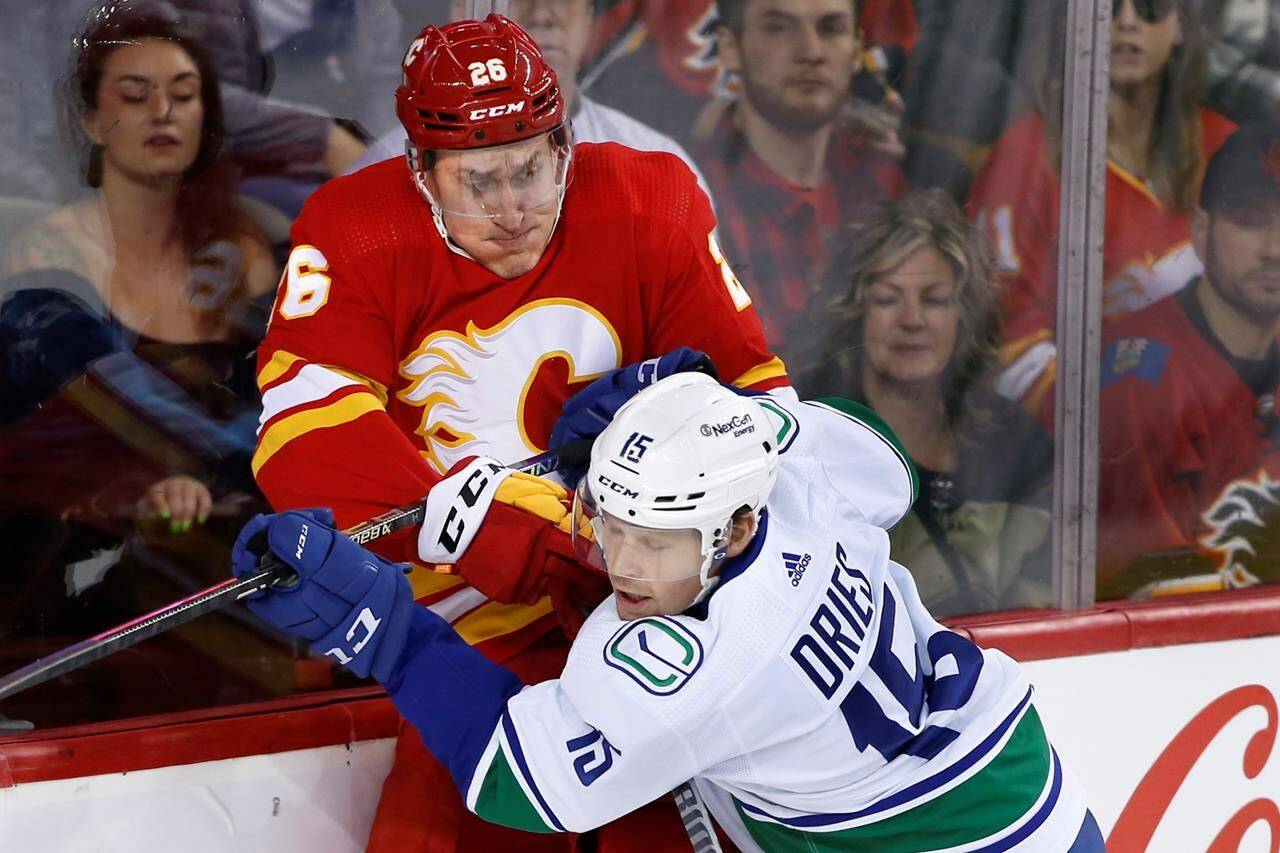 Vancouver Canucks’ Sheldon Dries, right, hits Calgary Flames’ Michael Stone during first period NHL hockey action in Calgary, Alta., Saturday, Dec. 31, 2022. THE CANADIAN PRESS/Larry MacDougal