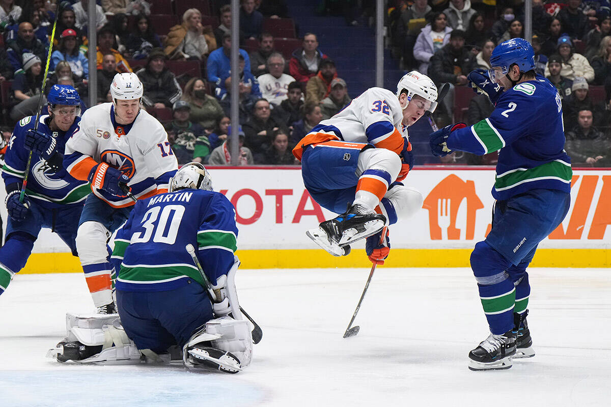 New York Islanders’ Ross Johnston (32) jumps out of the way to avoid being hit by the puck as Vancouver Canucks goalie Spencer Martin (30) makes the save while Luke Schenn (2), Travis Dermott (24) and New York’s Matt Martin (17) watch during the second period of an NHL hockey game in Vancouver, on Tuesday, January 3, 2023. THE CANADIAN PRESS/Darryl Dyck
