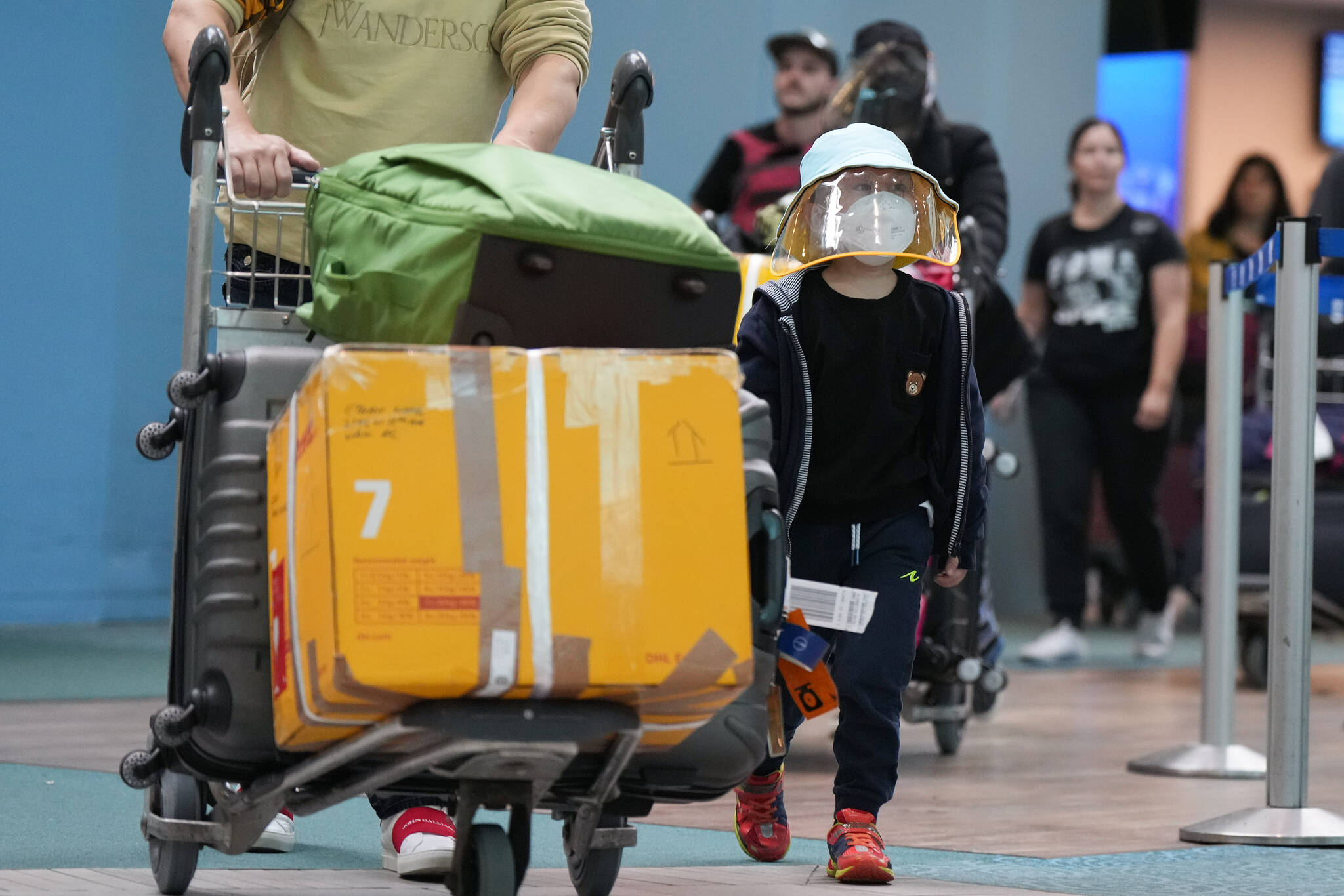A young boy who arrived on a Cathay Pacific flight from Hong Kong wears a face mask and face shield at Vancouver International Airport, in Richmond, B.C., on Wednesday, January 4, 2023. Starting Thursday, Canada will require air travellers from China, Hong Kong and Macau to have a recent negative COVID-19 test result. THE CANADIAN PRESS/Darryl Dyck