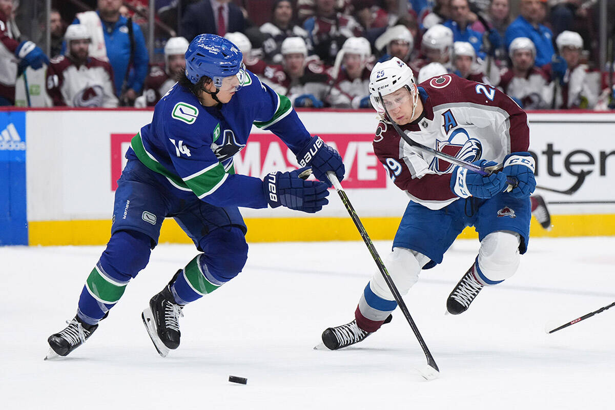 Vancouver Canucks’ Ethan Bear, left, and Colorado Avalanche’s Nathan MacKinnon vie for the puck during the second period of an NHL hockey game in Vancouver, on Thursday, January 5, 2023. THE CANADIAN PRESS/Darryl Dyck