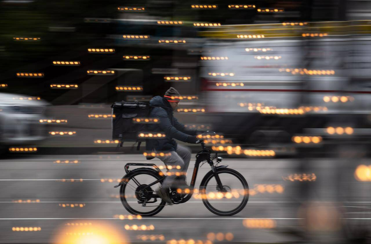 A food delivery worker rides a bike in downtown Vancouver, on Thursday, December 23, 2021. Gig work normally rises during a recession, but economists say a tight labour market and continued high inflation mean that might not happen in 2023. THE CANADIAN PRESS/Darryl Dyck