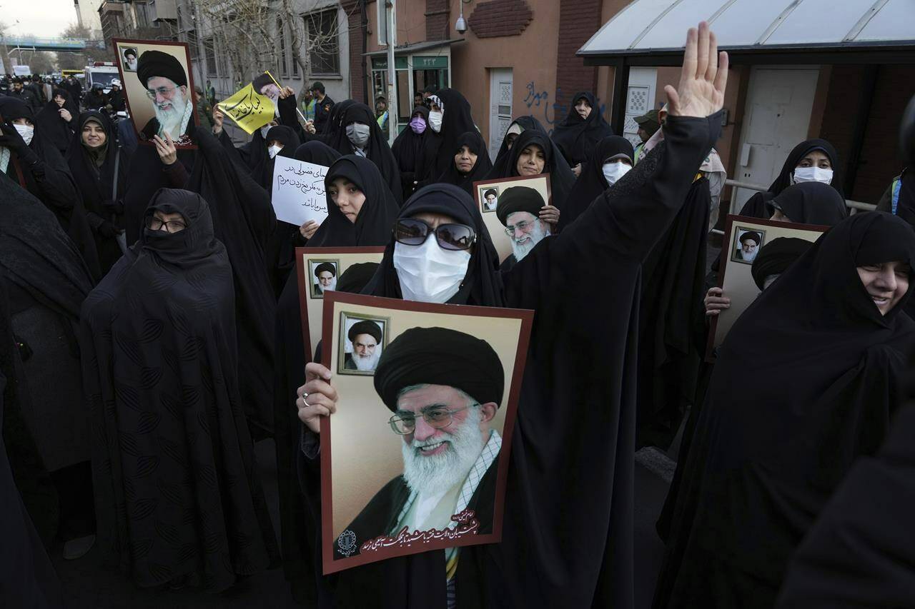 Iranian demonstrators chant slogans as they hold posters showing portraits of the Supreme Leader Ayatollah Ali Khamenei and late revolutionary founder Ayatollah Khomeini, top left on the poster, during their gathering to protest against the publication of offensive caricatures of Ayatollah Ali Khamenei in the French satirical magazine Charlie Hebdo, in front of the French Embassy in Tehran, Iran, Jan. 8, 2023. (AP Photo/Vahid Salemi)