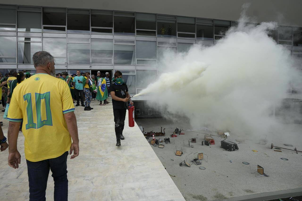 A protester, supporter of Brazil’s former President Jair Bolsonaro, empties a fire extinguisher after protesters stormed Planalto Palace in Brasilia, Brazil, Sunday, Jan. 8, 2023. Planalto is the official workplace of the president. (AP Photo/Eraldo Peres)