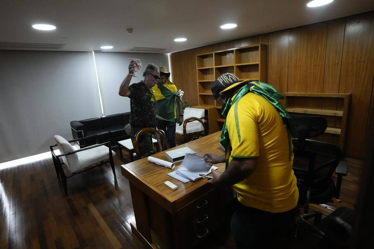 Protesters, supporters of Brazil's former President Jair Bolsonaro, rifle through papers on a desk after storming the Planalto Palace in Brasilia, Brazil, Sunday, Jan. 8, 2023. Planalto is the official workplace of the president of Brazil. (AP Photo/Eraldo Peres)