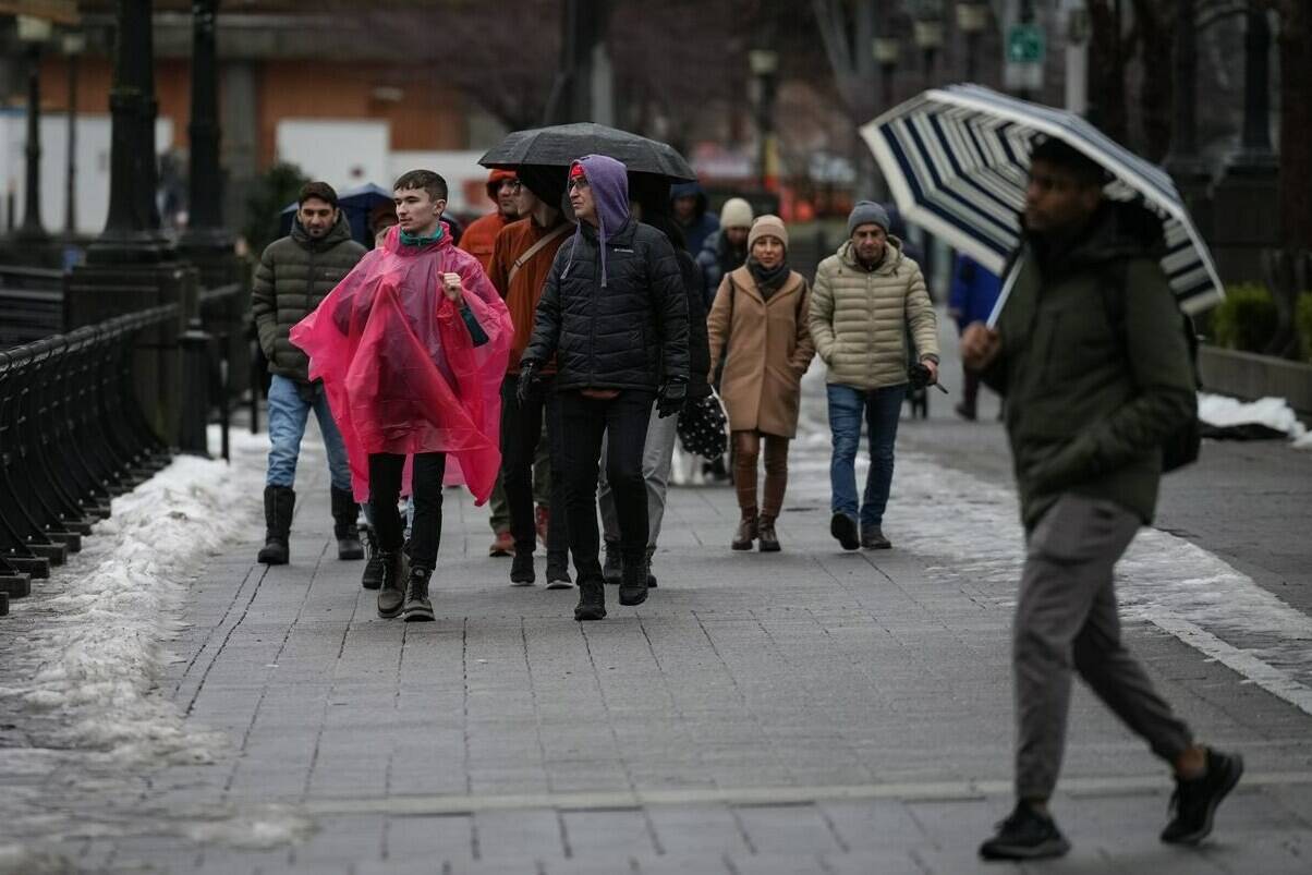 Flood watches are up for several regions of Vancouver Island and the inner south coast as another day of heavy rain, combined with snowmelt and a leap in freezing levels, could push some southwestern British Columbia waterways over their banks. People walk along the seawall as rain falls in downtown Vancouver, Sunday, Dec. 25, 2022. THE CANADIAN PRESS/Darryl Dyck