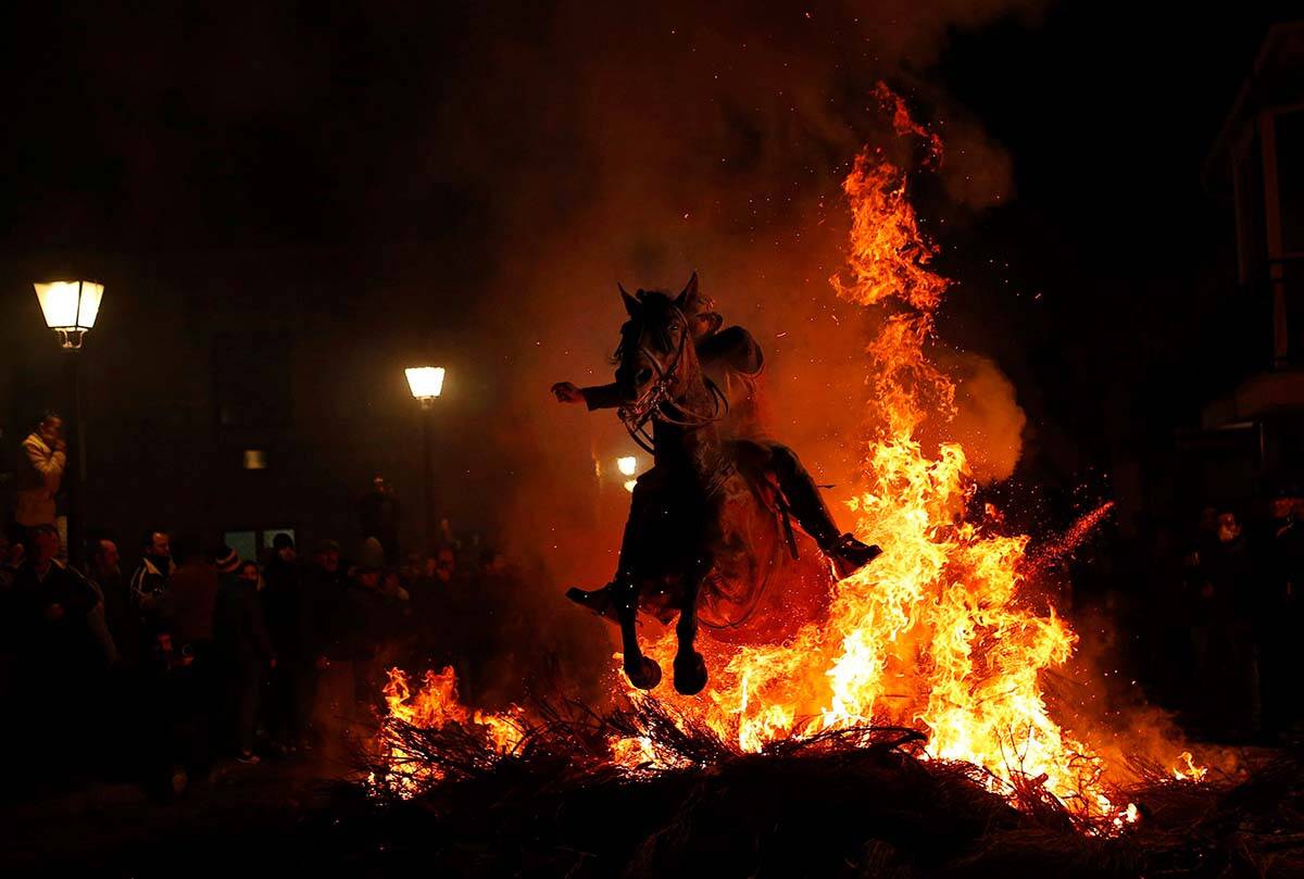 A man rides a horse through a bonfire as part of a ritual in honor of Saint Anthony the Abbot, the patron saint of animals, in San Bartolome de Pinares, Spain, Tuesday, Jan. 16, 2018. Horses burst through the soaring flames of night-time bonfires in a dramatic annual festival in this small Spanish town. The bonfires are called “luminarias,” and the Las Luminarias festival is believed to be centuries-old. (AP Photo/Francisco Seco)