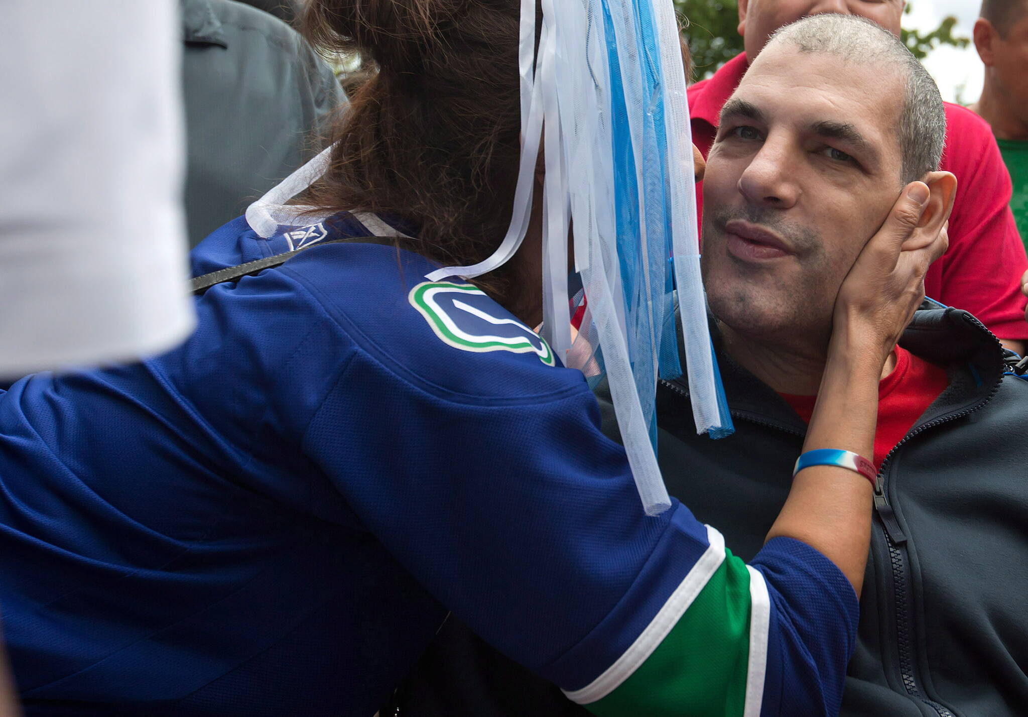 Violet Boehm, left, kisses former Vancouver Canucks’ enforcer Gino Odjick as he’s wheeled back into Vancouver General Hospital after coming out to greet hundreds of fans that gathered to support him in Vancouver, B.C., on Sunday June 29, 2014. THE CANADIAN PRESS/Darryl Dyck
