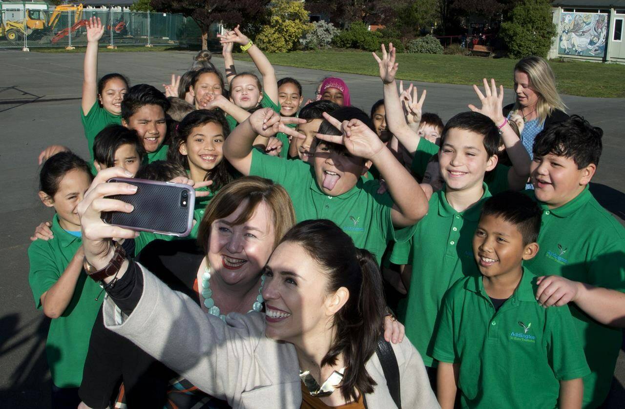 FILE - New Zealand Labour Party leader Jacinda Ardern, center right in front, poses for a selfie with students of Addington School in Christchurch, New Zealand, on Aug. 16, 2017. Ardern became an inspiration to women around the world after winning the top job in 2017 at the relatively young age of 37. (AP Photo/Mark Baker, File)