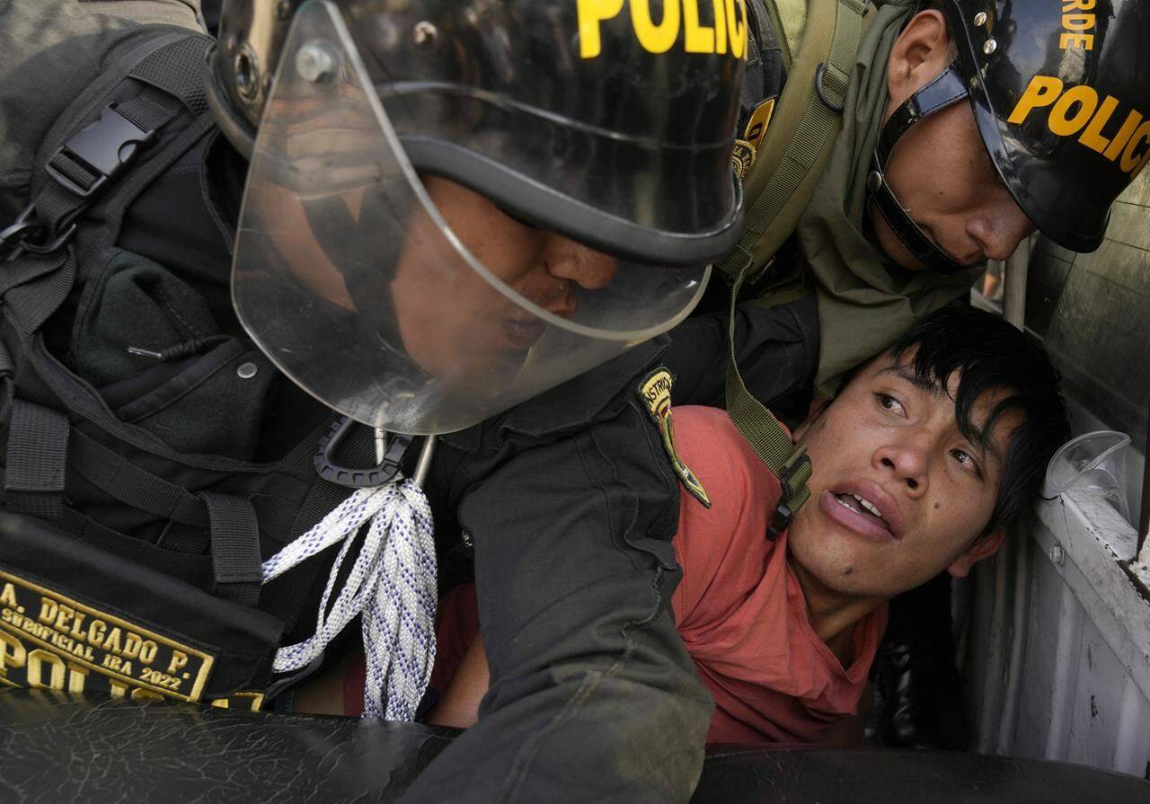 An anti-government protesters who traveled to the capital from across the country to march against Peruvian President Dina Boluarte, is detained and thrown on the back of police vehicle during clashes in Lima, Peru, Thursday, Jan. 19, 2023. Protesters are seeking immediate elections, Boluarte’s resignation, the release of ousted President Pedro Castillo and justice for up to 48 protesters killed in clashes with police. (AP Photo/Martin Mejia)